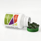 Green capsules sitting next to white bottle falling over onto lid